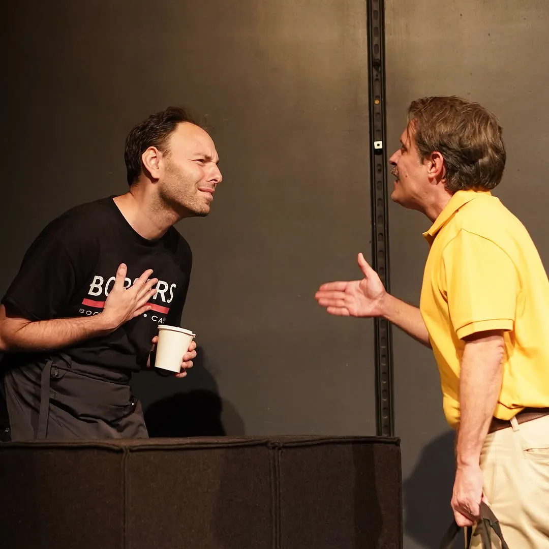 The barista in a Borders t-shirt faces off with a customer in a yellow polo.