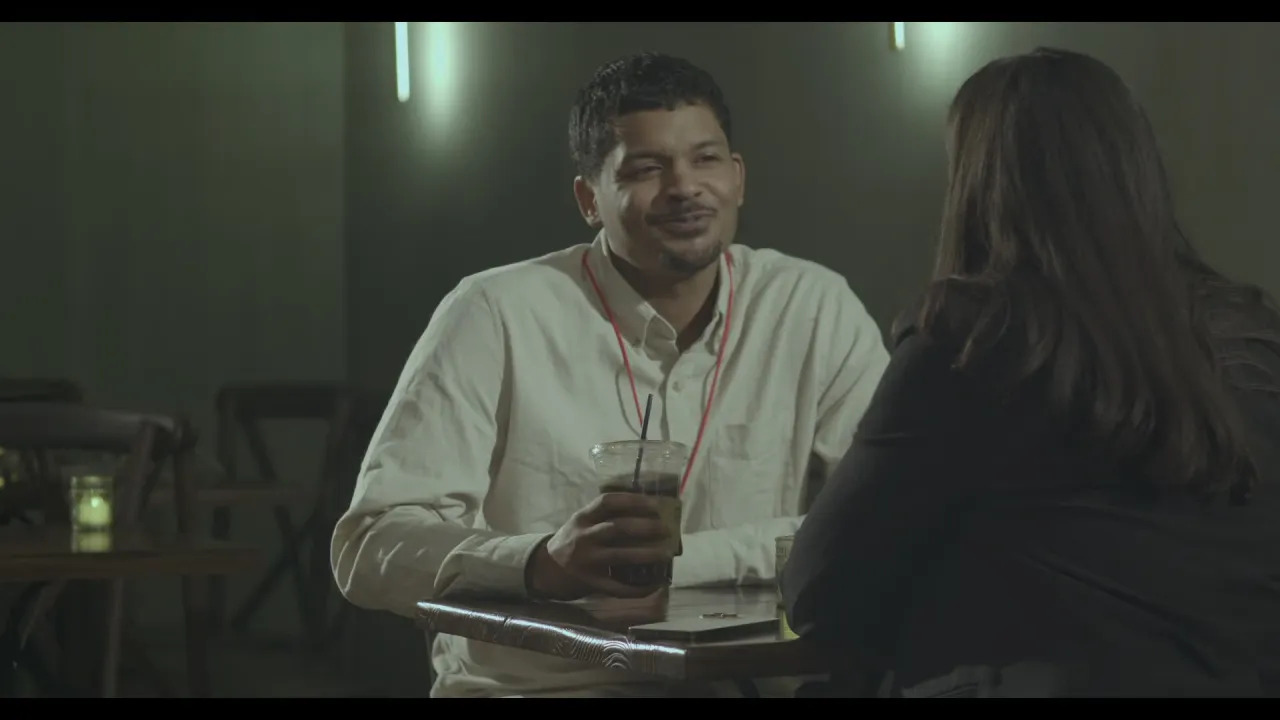 Two characters face each other across a bar table.