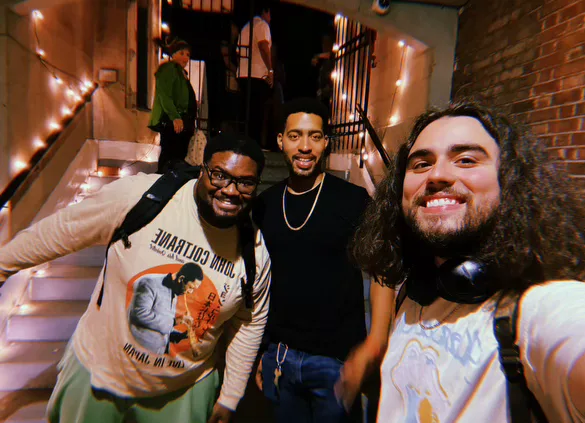 Three members of the company outside the venue under string lights.